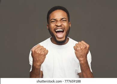 Winner Celebrates. Great Success. Excited Black Man With Happy Facial Expression On White Studio Background