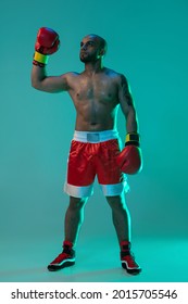 Winner, Champion. One Young Professional Male Boxer Standing Isolated On Blue Green Background In Neon Light. Full Length. Healthy Lifestyle, Sport And Motion Concept. Copy Space For Ad.