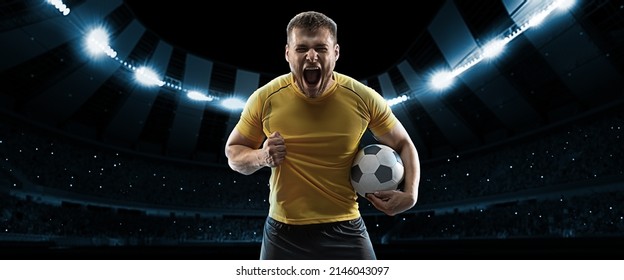 Winner emotions. One professional soccer, football player in football kit standing with ball over dark night stadium with flashlights background. Sport, competition, championship, wow emotion. - Powered by Shutterstock