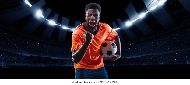 Winner emotions.Excited professional soccer, football player in football kit standing with ball and shouting over dark night stadium with flashlights background. Sport, competition, championship, wow - Shutterstock ID 2148627387