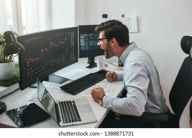 I Am A Winner! Happy Young Trader In Formalwear And Eyeglasses Shouting And Feeling Excited While Looking At Trading Charts And Financial Data In The Office.