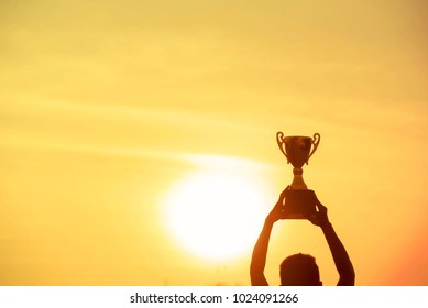 Winner Holding Golden Trophy Cup. Silhouette Best Award Victory Trophy For Professional Champion Challenge Man Holding Trophy Cup Over Head Success In Goal. Win-Win Business Concept.