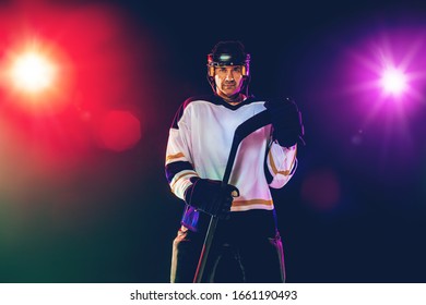 Winner. Male hockey player with the stick on ice court and dark neon colored background. Sportsman wearing equipment, helmet practicing. Concept of sport, healthy lifestyle, motion, wellness, action. - Shutterstock ID 1661190493