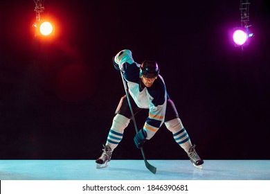 Winner. Male hockey player with the stick on ice court and dark neon colored background. Sportsman wearing equipment, helmet practicing. Concept of sport, healthy lifestyle, motion, wellness, action. - Powered by Shutterstock