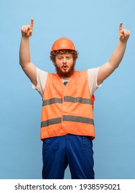 Winner. Portrait Of Caucasian Red-headed Man Builder In Orange Working Uniform Isolated On Blue Background. Concept Of Human Facial Expression, Work, Action, Funny Meme Emotions. Copy Space For Ad.