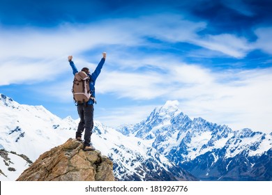 Winner / Success concept. Hiker cheering elated and blissful with arms raised in the sky after hiking to mountain top summit above the clouds 