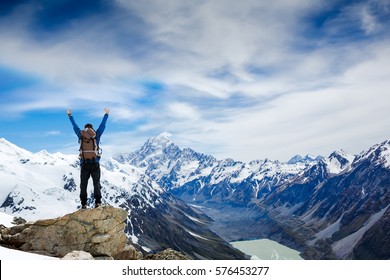 Winner / Success Concept. Hiker Cheering Elated And Blissful With Arms Raised In The Sky After Hiking To Mountain Top Summit Above The Clouds. Mt Cook National Park. New Zealand