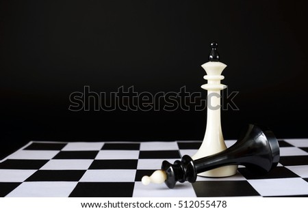 Winner and Vanquished. Fallen chess king near another one. Concept with chess pieces against black background