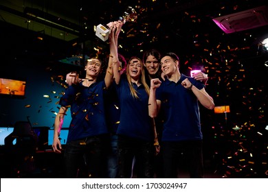 Winners of cybersports championship raising golden award while celebrating winning under falling confetti - Powered by Shutterstock