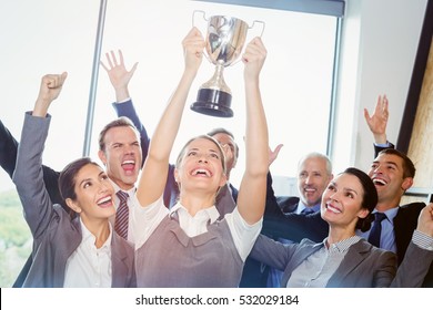 Winning business team with a woman executive holding a gold trophy