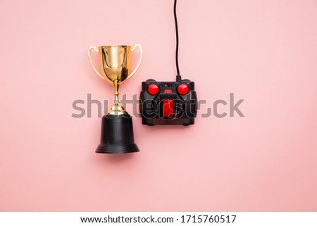 winning gamer. A retro games joystick with a gold winning trophy