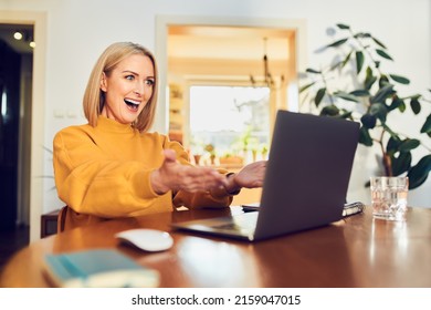 Winning happy middle aged woman celebrating success looking on laptop at home                               