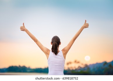 Winning, success and life goals concept. Young woman with arms in the air giving thumbs up. - Shutterstock ID 639818752