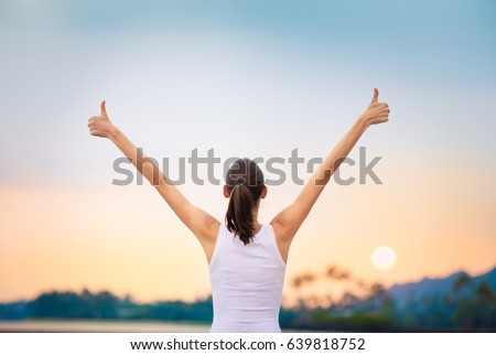 Winning, success and life goals concept. Young woman with arms in the air giving thumbs up.