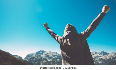 Winning and success. Victorious female person standing on mountain top with arms raised in V. Achievement and accomplishment in life. Toned image. - Shutterstock ID 723287881
