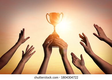 Winning team with gold trophy cup against shining sun in sky  - Shutterstock ID 1804304722