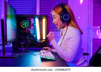 Winning Victory. Asian Gamer Playing Online Video Game Excited On Desktop Computer PC Colorful Neon LED Lights, Woman In Gaming Headphones Use Computer She Happy Successful, E-Sport Concept, Side View