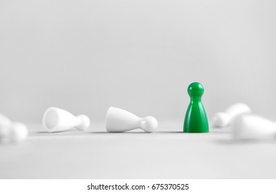 Winning, victory, success and surviving concept. Green board game pawn stand alone, the white rest fallen. Eliminating competitors. One against the others. Last man standing. Against all odds. - Shutterstock ID 675370525