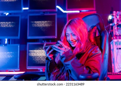 Winning or You Win. Young woman gamer champion excited, Happy gamer people playing video game online with smart mobile phone with neon lights raises hands to wins celebrating, game and e-sports. - Shutterstock ID 2231163489