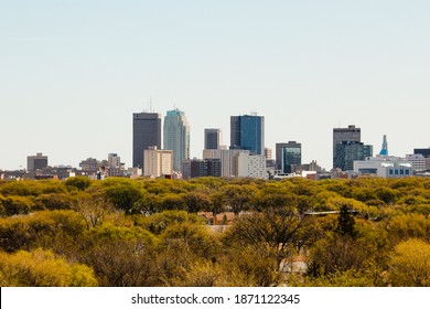 WINNIPEG, MANITOBA, CANADA – MAY 12, 2017: Winnipeg skyline with buildings of Richardson Building, MTS, RBC Royal Bank, Radisson Hotel, and Artis on a sunny day with trees in the foreground.