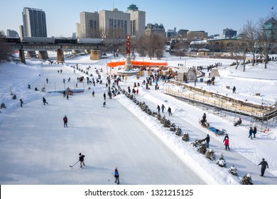 Winnipeg, Manitoba/Canada - February 2019: People skating at the Red River Mutual Skate Trail and playing hockey at an outdoor rink at the Forks on a sunny afternoon