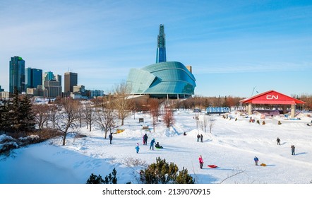 Winnipeg, MB, Canada - March 2022: People Enjoying Winter Activities At The Forks With A View Of The Esplanade Riel, The Canadian Museum For Human Rights, And Downtown Winnipeg In The Background