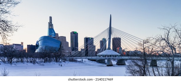 Winnipeg, MB, Canada - March 2022: A view of the Winnipeg skyline near dusk, featuring the Canadian Museum of Human Rights, the Esplanade Riel, and downtown Winnipeg over the frozen Red River