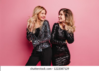 Winsome fair-haired girl laughing with best friend. Indoor photo of blissful caucasian ladies chilling at party.