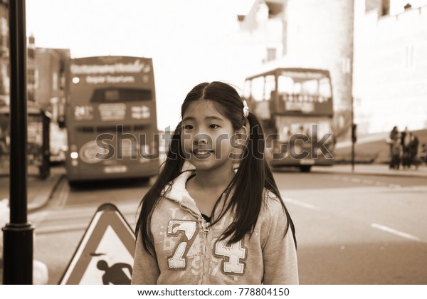 WINSOR –OCT 25  : Asian female tourist and\
double decker bus beside Windsor castle wall represent the british\
tourism industry concept related idea on October 25, 2015 in Winsor\
Hamshire, England.