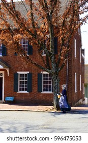 WINSTON-SALEM, USA, MAR 2017: A Lady In Traditional Moravian Costume Walks Past A Building In The Old Salem Museums And Gardens.