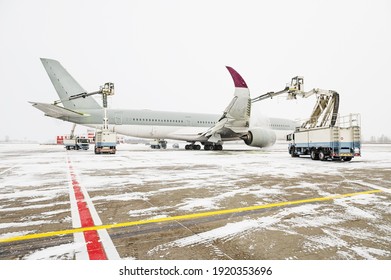 Winter at the airport. Snow storm. Airplane de-icing before take off. De-icing the aircraft before the flight. The de-icing machine sprinkles the wing of a passenger plane with de-icing fluid