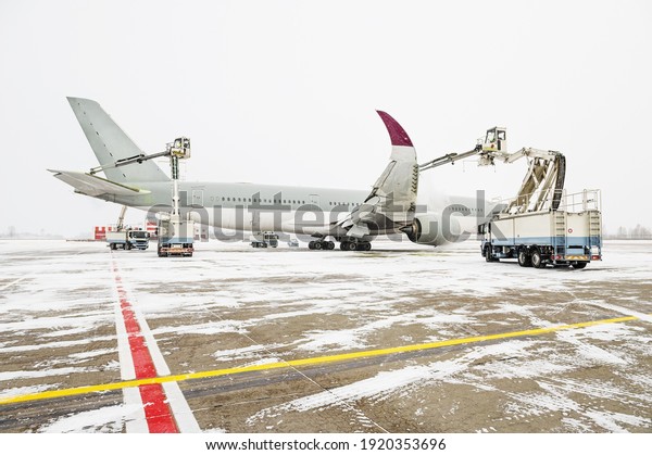 Winter at the airport. Snow storm. Airplane\
de-icing before take off. De-icing the aircraft before the flight.\
The de-icing machine sprinkles the wing of a passenger plane with\
de-icing fluid