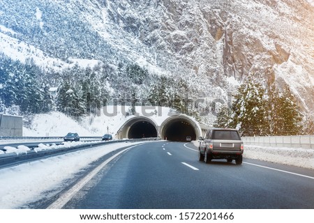 Winter alpine road landscape with tunnel, forest, mountains and blue sky on background at bright cold sunny day. Car trip family travel journey. Holiday skiing vacation. scenic austrian landscape