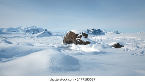 Winter Antarctic landscape in sunny day, blue sky. Desert white land of snow and ice, mountain range in background. Breathtaking travel journey over frozen Antarctica landscape. Low angle drone shot - Powered by Shutterstock