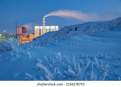 Winter arctic industrial landscape. View of the snow-covered mountain slope and the thermal power plant. Electric power industry in the Arctic. Cold frosty weather. Anadyr, Chukotka, Far North Russia.