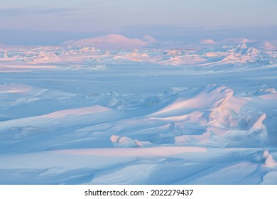 Winter arctic landscape. Cold frosty winter weather. Harsh polar climate. Ice hummocks on the frozen sea in the Arctic. View of snow and ice at sunset. Picturesque nature of the Arctic. Far North.