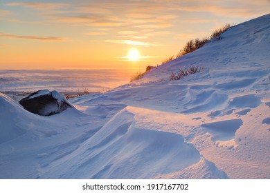 Winter Arctic Landscape. Morning View From The Snow-covered Mountainside To The Sunrise Over The Frozen Sea And Tundra. Cold Windy And Frosty Weather. Beautiful Sunrise. Chukotka, Siberia, Russia.