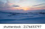 Winter arctic landscape. Sunset in the tundra. Early winter twilight. Cold frosty winter weather. Electric poles and satellite dishes in the snowy tundra. Chukotka, Siberia, Far East of Russia, Arctic