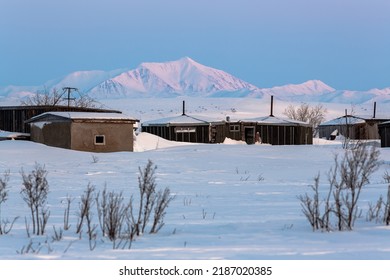 Winter Arctic Landscape. View Of An Abandoned Settlement In The Snowy Tundra. Old Houses Among The Snow. Hard-to-reach Terrain In The Far North Of Russia. Chukotka, Siberia. Polar Region. Cold Weather