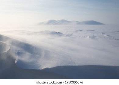 Winter Arctic Landscape. View Of The Snow-covered Tundra And Snow-covered Mountains. Very Cold And Windy Weather. Blowing Blizzard. Chukotka, Siberia, Russia. Low Depth Of Field, Blurred Background.