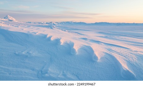 Winter arctic landscape. Weathered old animal footprints in the snow. View of snow and ice at sunset. Snow-covered expanses of the Arctic. Cold frosty winter weather. Harsh polar climate. Far North. - Powered by Shutterstock