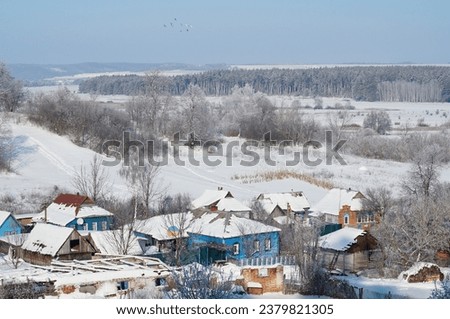 Winter atmosphere in the village, frost on the trees and a snowy rural house.