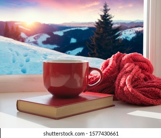 Winter Background - Cup With Candy Cane, Woolen Scarf And Gloves On Windowsill And Winter Scene Outdoors. Still Life With Concept Of Spending Winter Time At Cozy Home With Cold Weather Outdoors