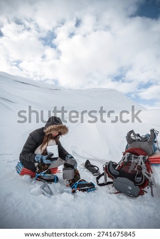 Winter backpacker resting in remote snowy mountains, minimalist outdoor expedition, solitude and endurance