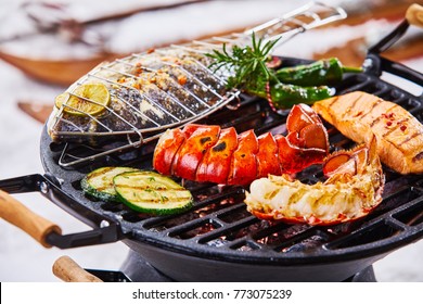 Winter barbecue with gourmet seafood grilling over the hot coals including a lobster tail, salmon and whole marine fish seasoned with herbs