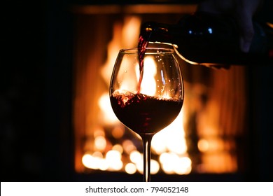 In Winter, Before The Fireplace, Is Poured, Tasted Red Wine In A Glass. Concept Of: Relax, Restaurant, Wine, Sommelier.