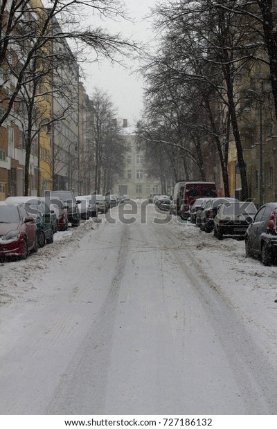 Winter in Berlin - A street with\
residential buildings in Berlin is completely covered with snow.\
The cars, the walkway and also the street is covered with white\
powder. It is cold and\
uncomfortable.