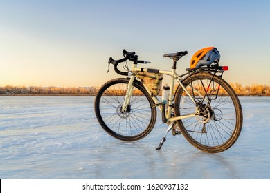 Winter biking, touring or commuting - bicycle on an icy lake. Helmet on racks, frame bag, kickstand. Riverbend Ponds Natural Area in Fort Collins, Colorado