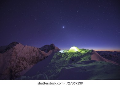 Winter Camping In High Mountains. High Tatra, Slovakia. Lid Tent Shining On A Mountian Ridge. Stars, Starry Night, Winter Climbing And Mountaineering.