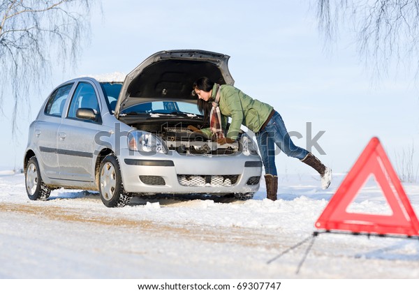 Winter car\
breakdown - woman try to repair\
motor